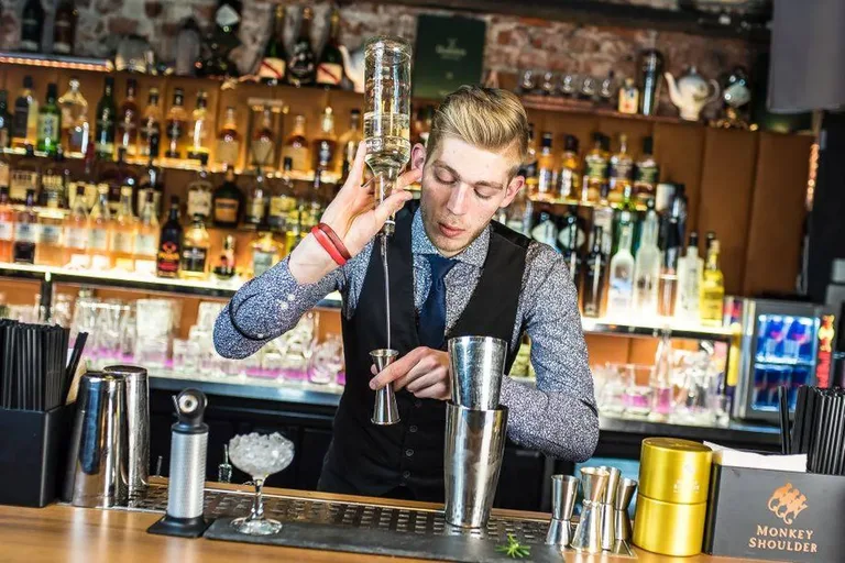 Barman odměřuje suroviny koktejlu u baru v Cocktail Roomu Zakopane